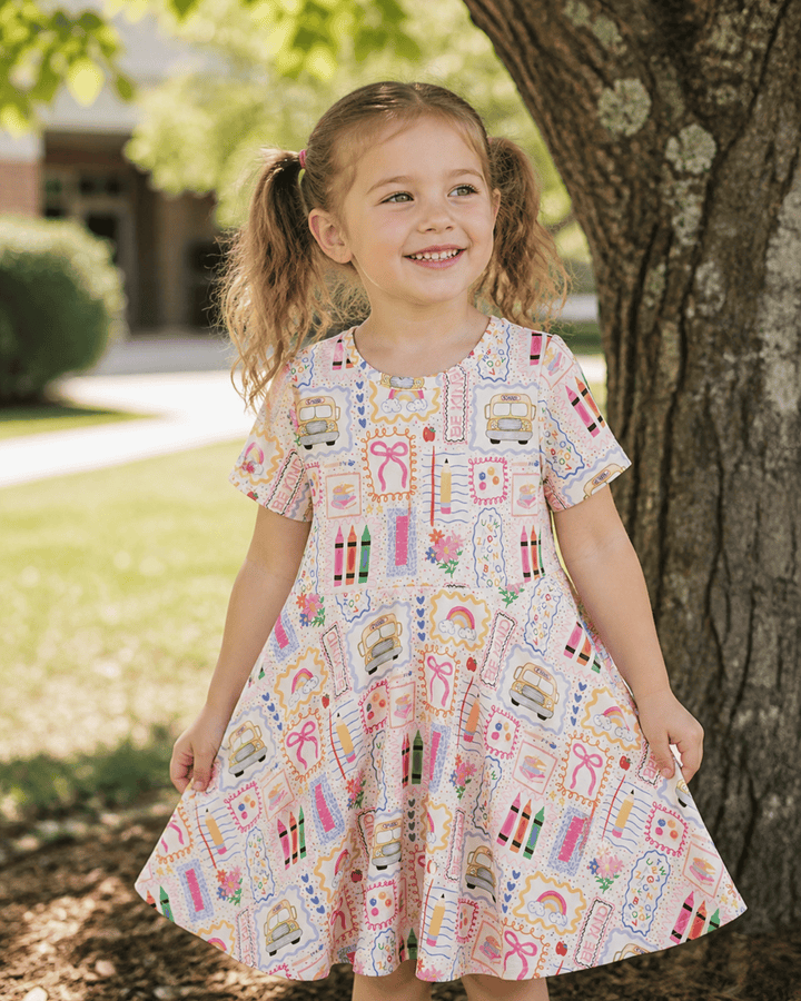 Toddler girl in dress with pencils by tree
