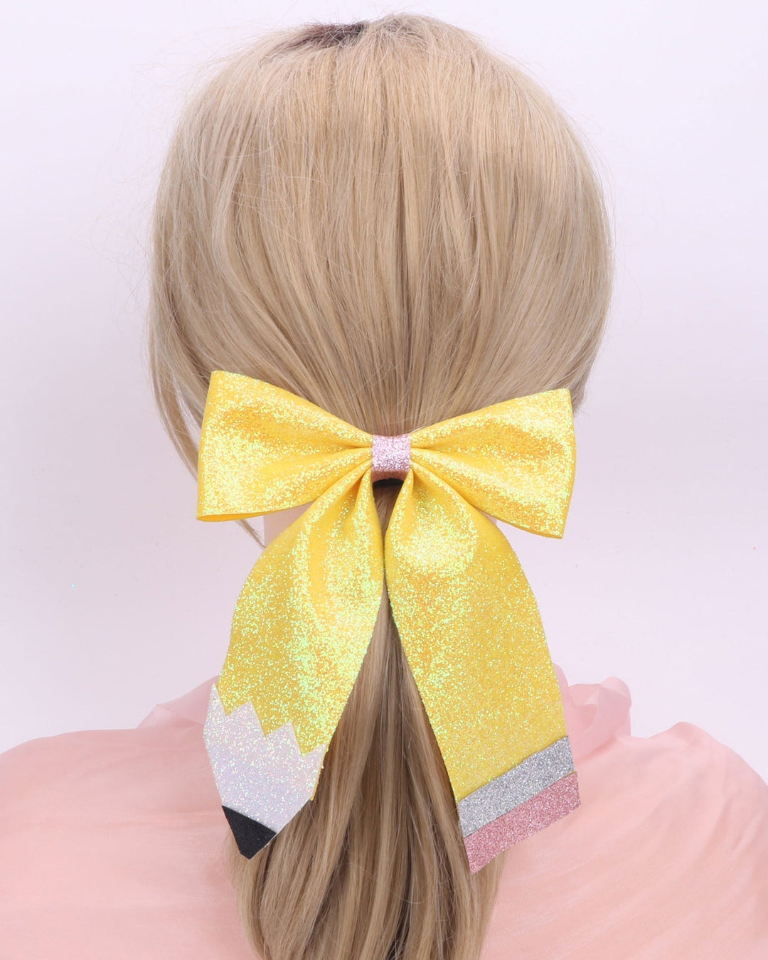 Yellow hair bow with a white and pink base on a plain background