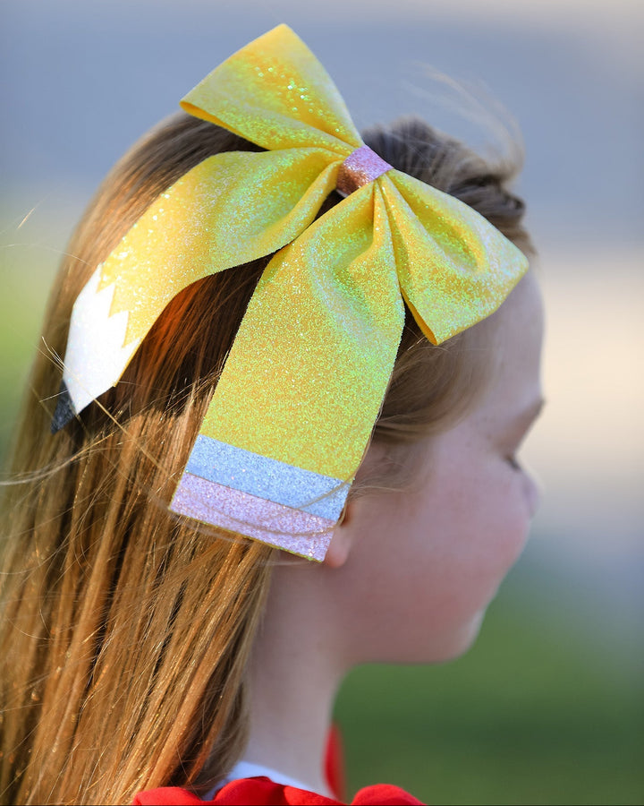 Close-up of a large yellow hair bow on a blurred outdoor background
