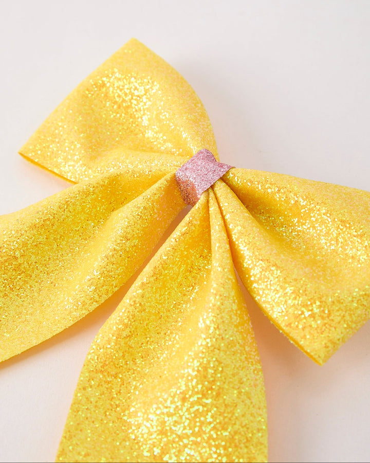 Yellow glittery bow on a light background