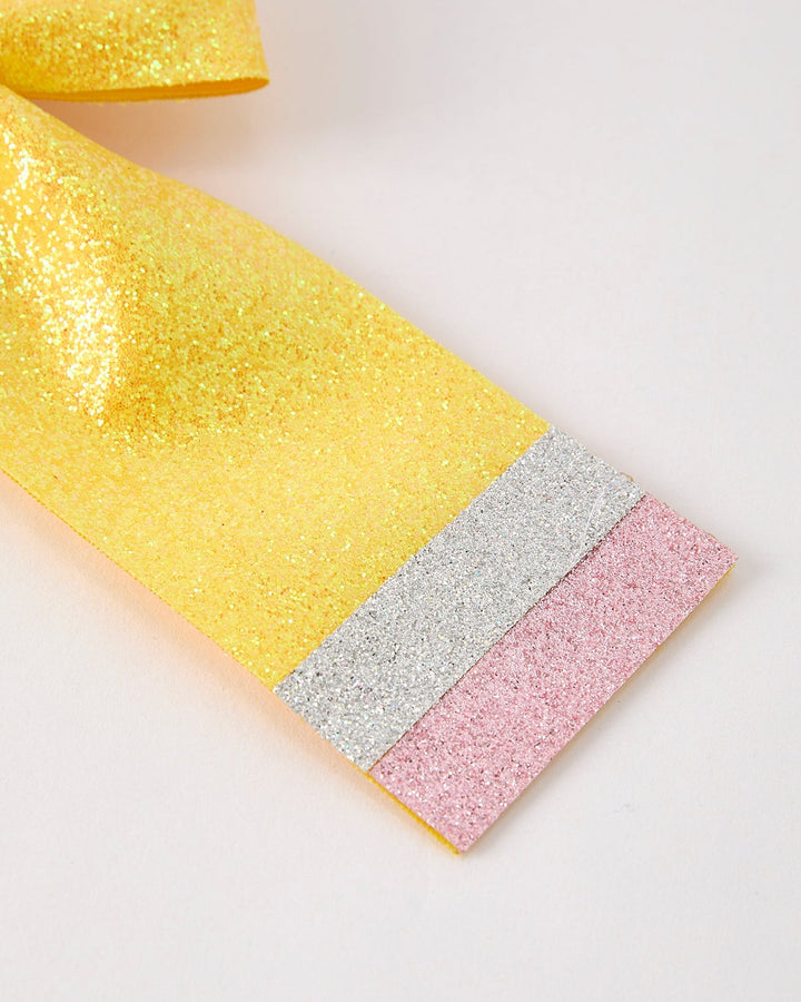 Close-up of a glittery fabric with yellow, silver, and pink colors on a light background.