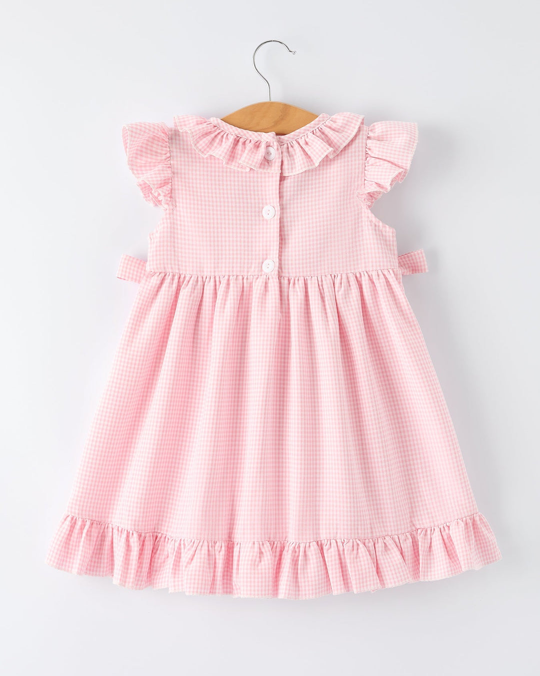 Pink checkered dress on a hanger against a light gray background