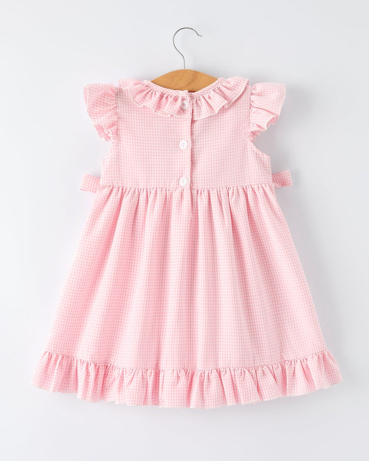 Pink checkered dress on a hanger against a light gray background