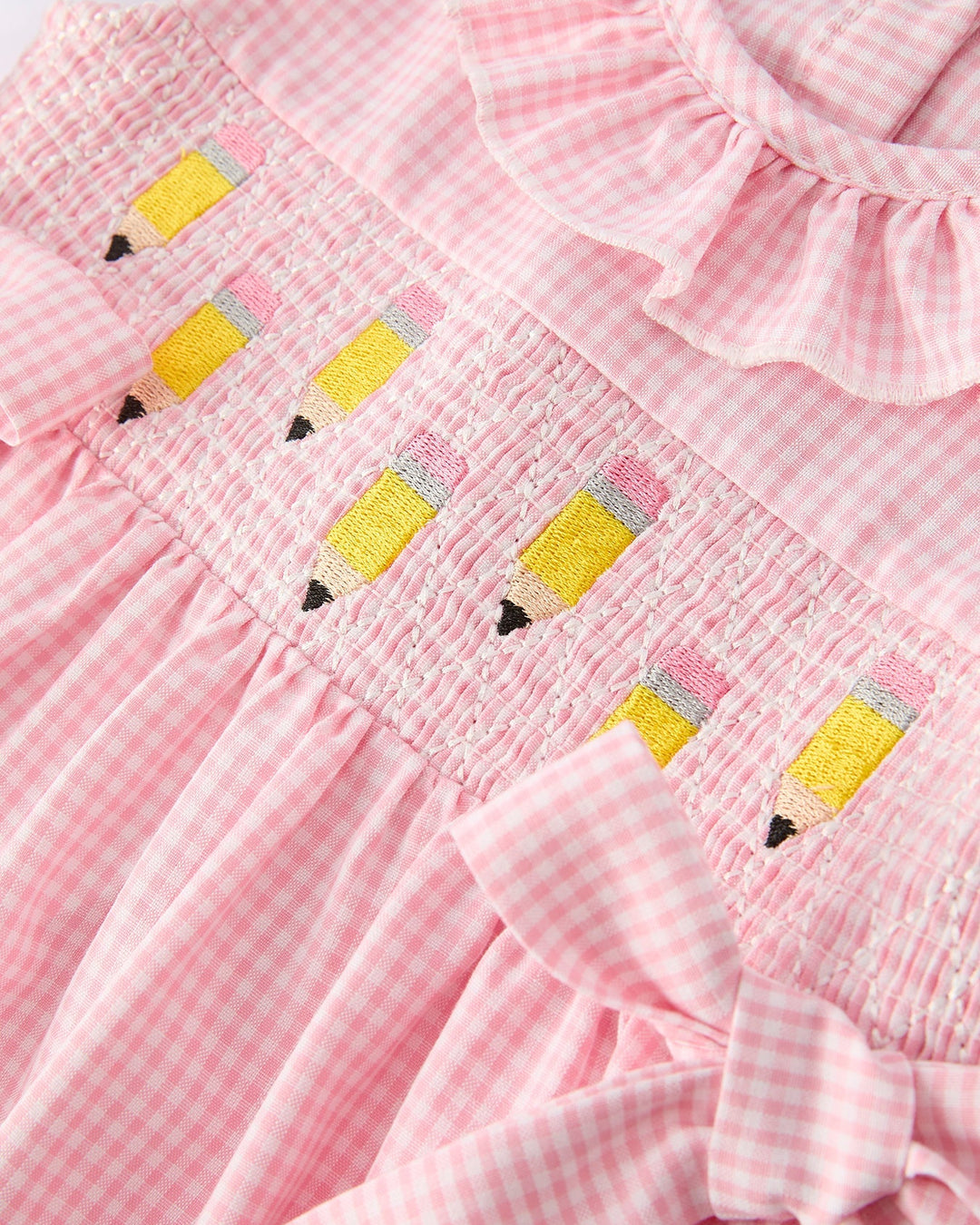 Pink checkered dress with pencil designs on a white background