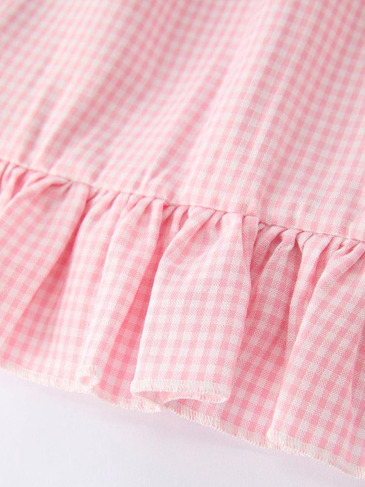 Close-up of a pink gingham dress with ruffled hem on a white background
