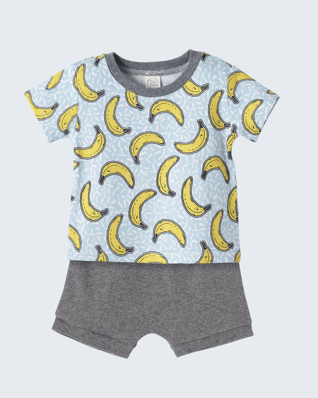 Children's outfit with banana pattern shirt and gray shorts on a light blue background