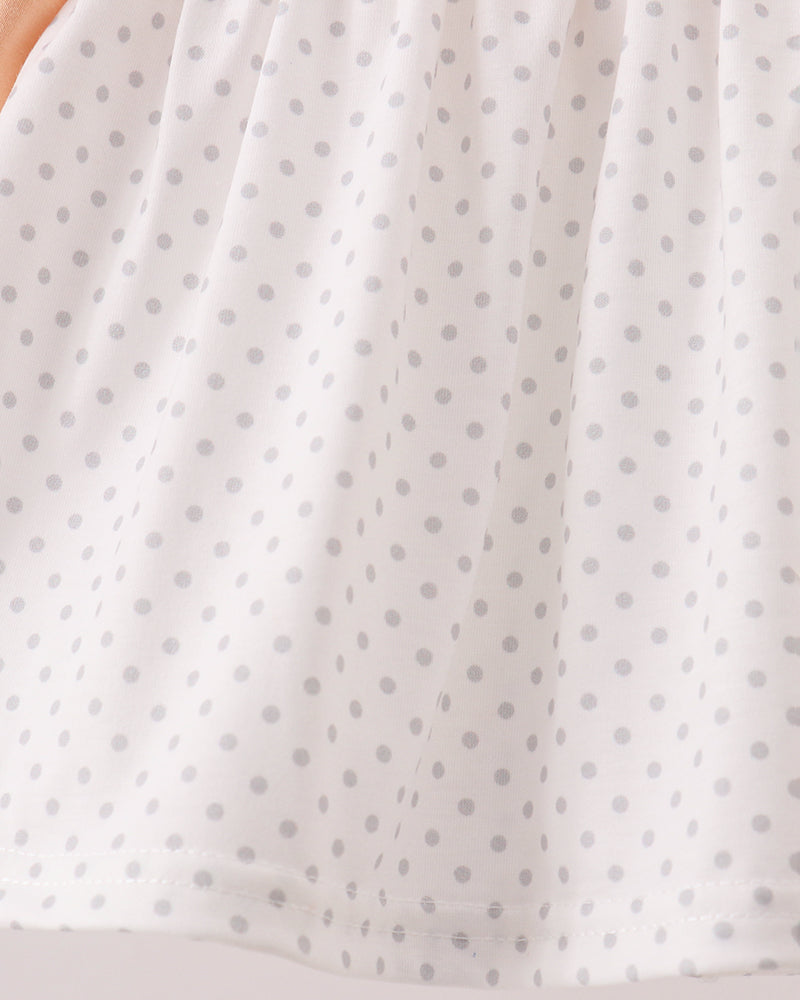 A close-up of a white fabric with a repeating light gray polka dot pattern, showing the texture and drape of the material.
