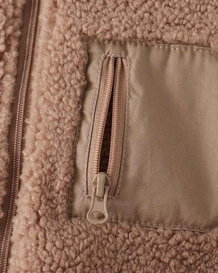 Beige fleece jacket detail: front zipper and flap pocket with lining