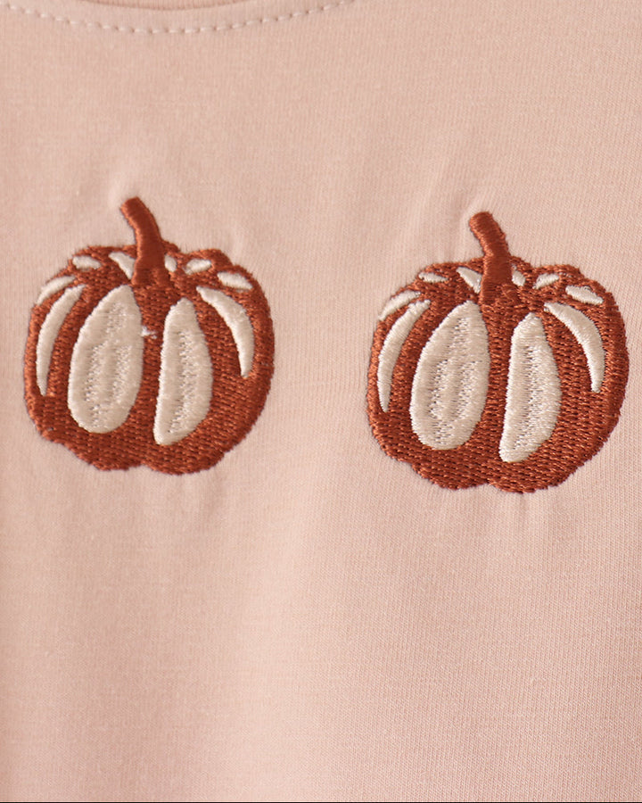 Beige romper front detail: embroidered brown pumpkin faces with white accents.