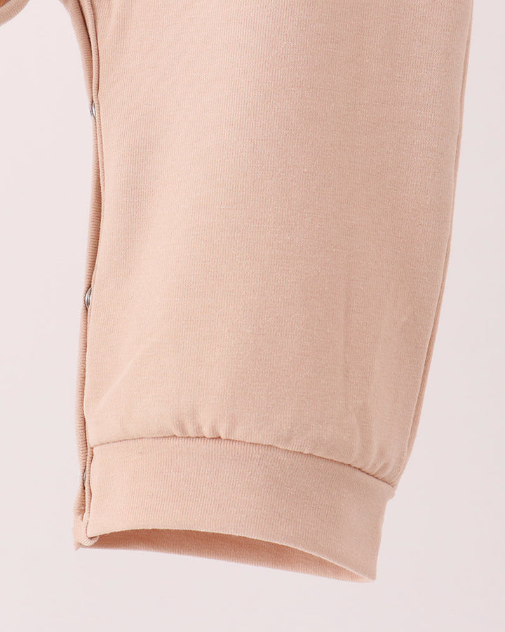 Beige footed romper with ribbed ankle cuffs and smooth leg panels.