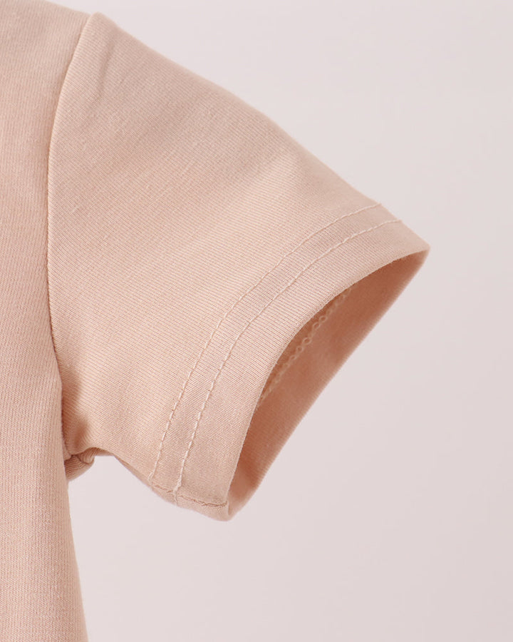Beige romper sleeve cuff with stitched hem detail and curved neckline edge.