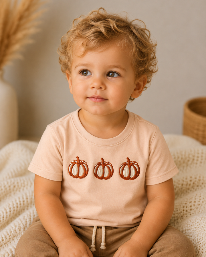 Beige pumpkin-embroidered tee on child, short sleeves