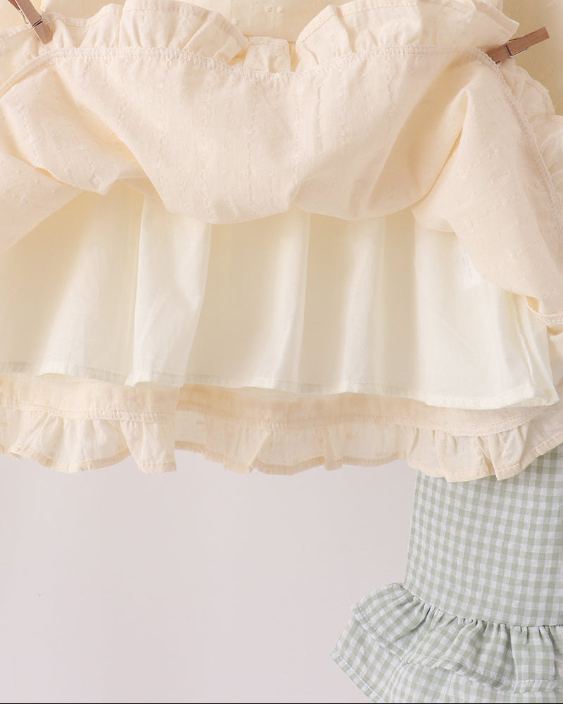 Cream ruffle blouse with gathered neckline and layered hem, paired with gingham pants
