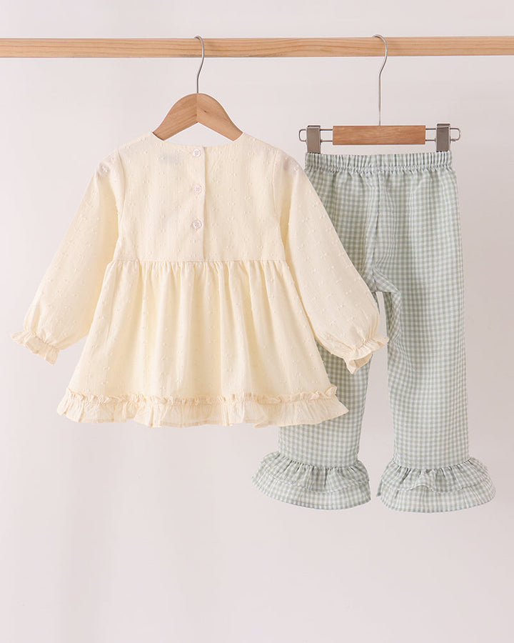 Cream long-sleeve ruffle dress and green gingham ruffle pants set on hangers