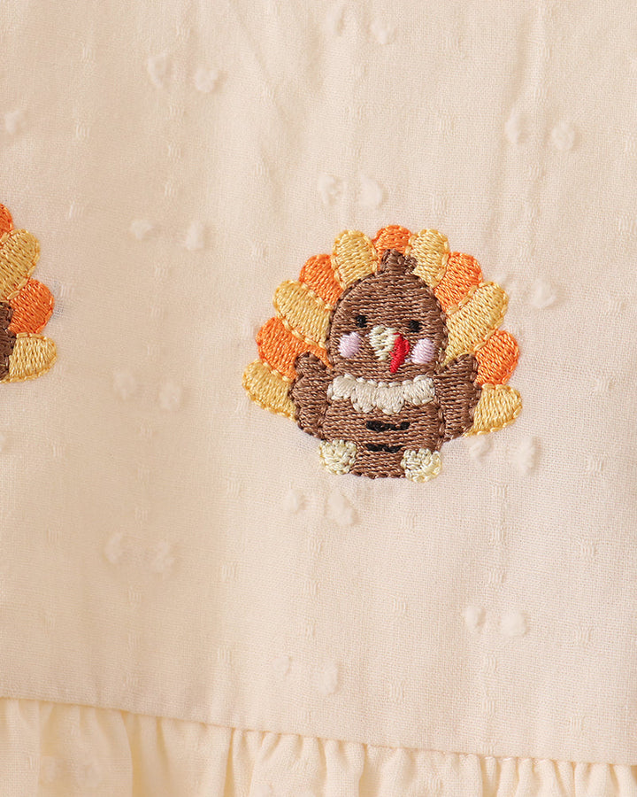 Cream romper with turkey-themed beaded embroidery on front yoke