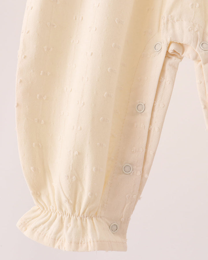 Cream romper leg with buttoned snap at ankle and elastic cuff