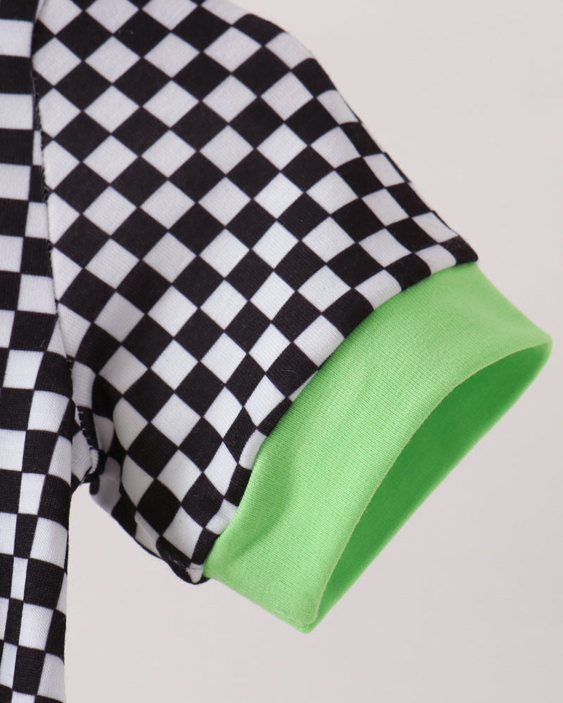 Close-up of a short-sleeve shirt sleeve with a black and white checkerboard pattern and a bright lime green ribbed cuff, shown against a light neutral background.