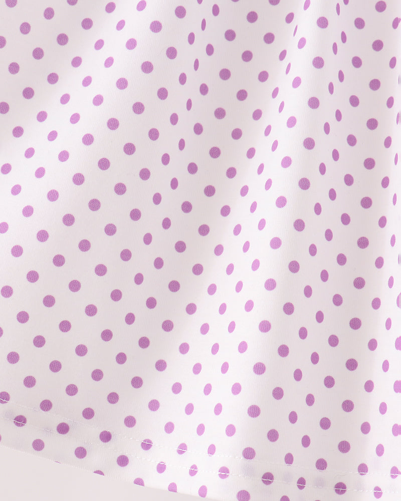 White fabric with a repeating pattern of small purple polka dots, shown in a close-up view with soft folds.