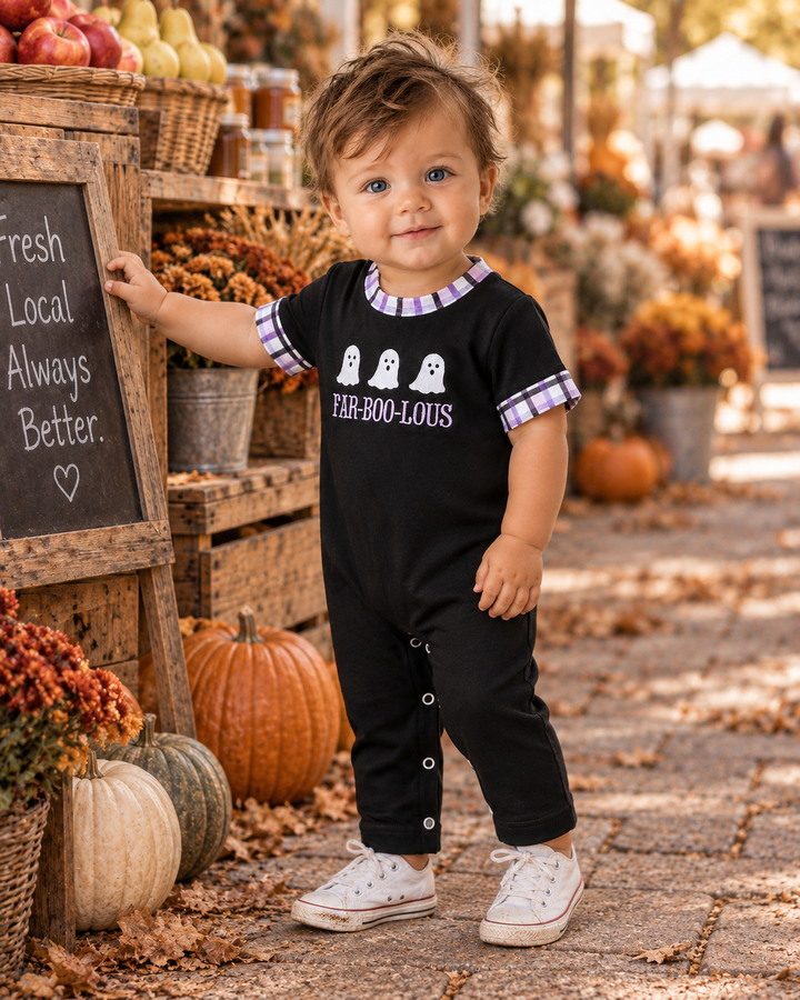 Baby boy in a cute Halloween romper in outdoor fall setting.
