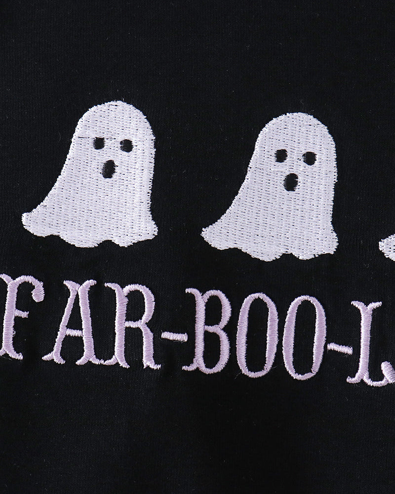 Close-up of a black garment featuring two white embroidered ghosts and the partial text &