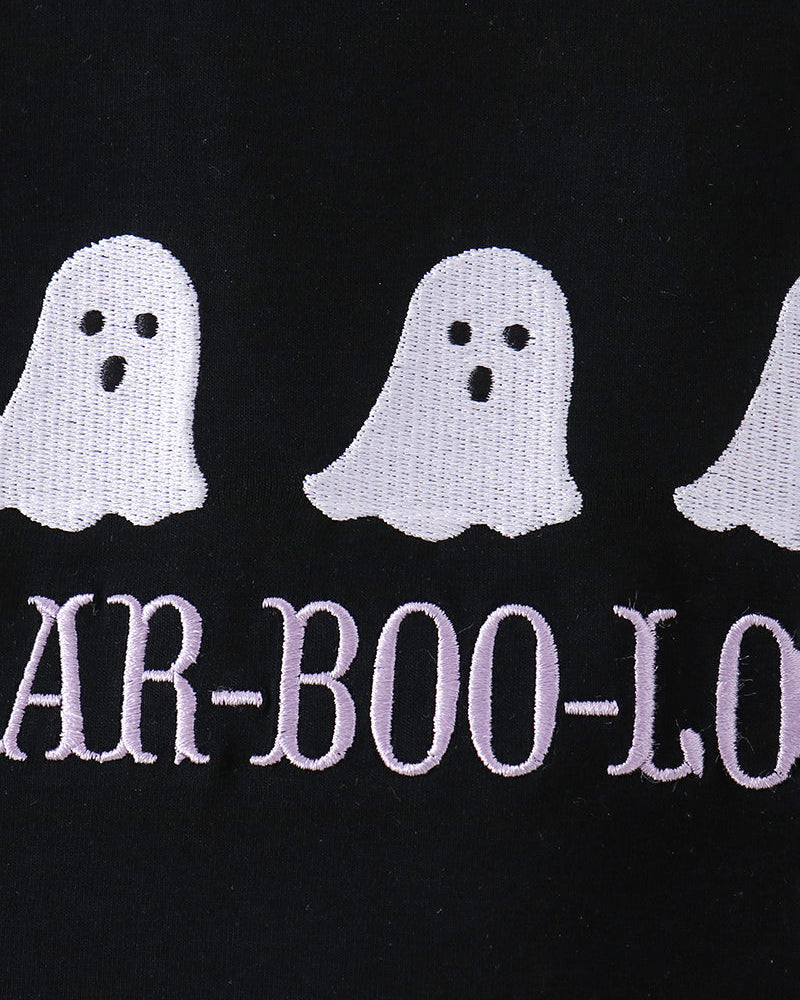 Close-up of a black garment featuring embroidered white ghosts and the text &