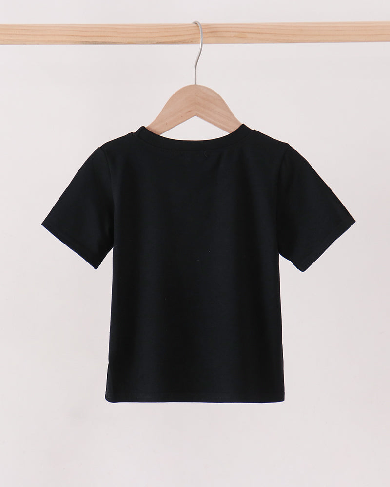 A black short-sleeve crewneck t-shirt hanging on a wooden hanger from a light wood clothing rack against a plain off-white background.