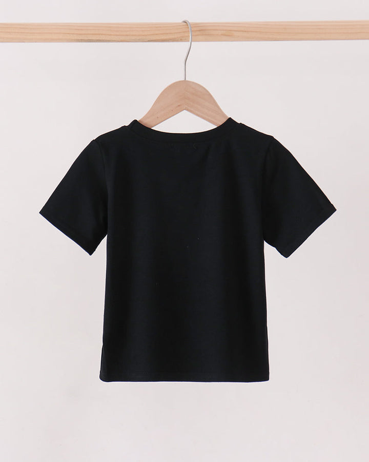 A black short-sleeve crewneck t-shirt hanging on a wooden hanger from a light wood clothing rack against a plain off-white background.
