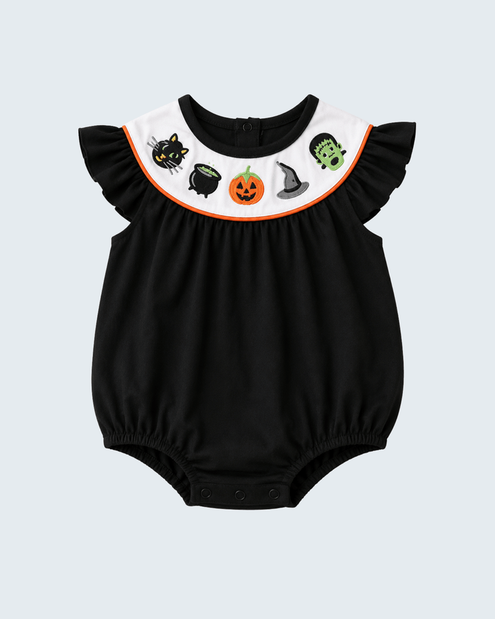 A baby romper in black with a white ruffled collar decorated with Halloween-themed illustrations including a black cat, cauldron, pumpkin, witch hat, and Frankenstein&