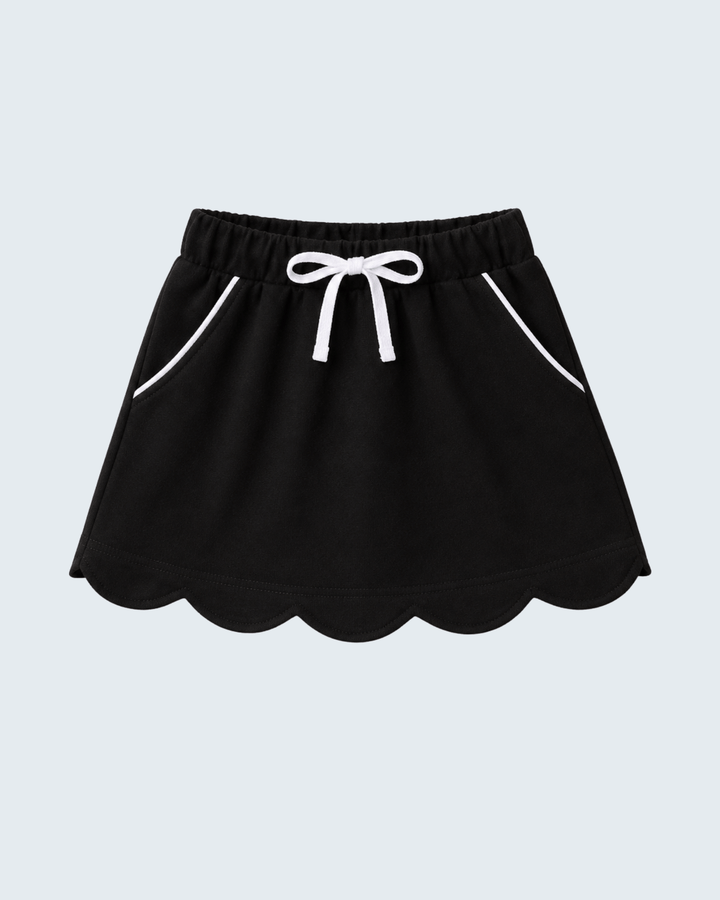 A black mini skirt with a scalloped hem, white drawstring bow at the elastic waist, and white piping details on the side pockets, shown against a light gray background.