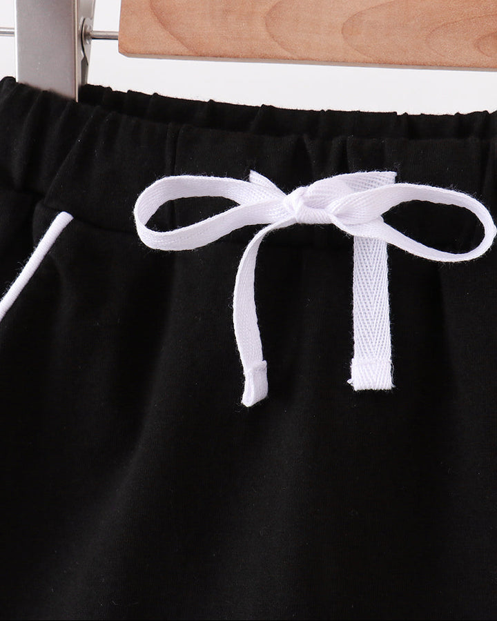 Black skort with scalloped hem and white bow at elastic waistband