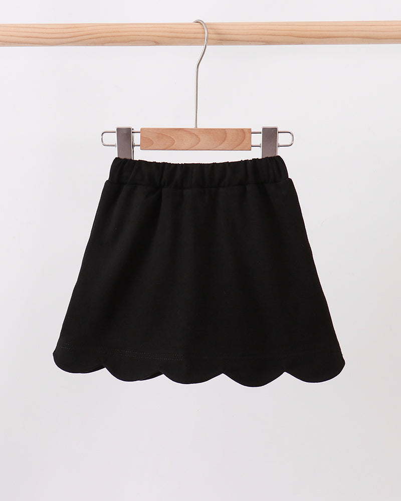 Black skort with scalloped hem, elastic waistband, and white bow ties