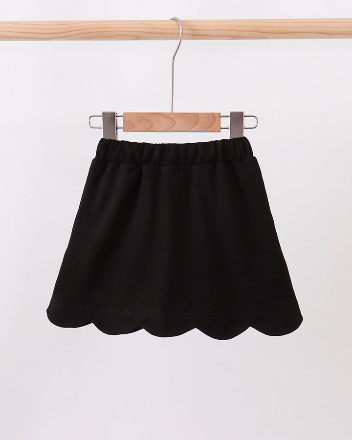 Black skort with scalloped hem, elastic waistband, and white bow ties