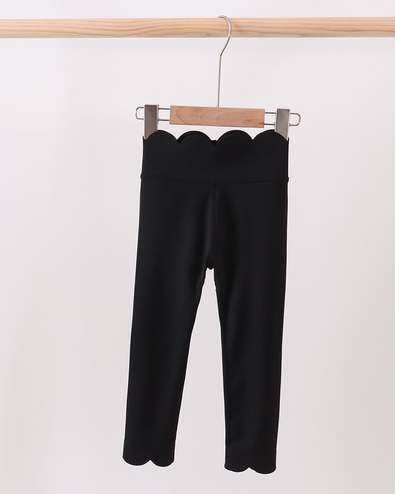Black pants hanging on a wooden hanger against a white background