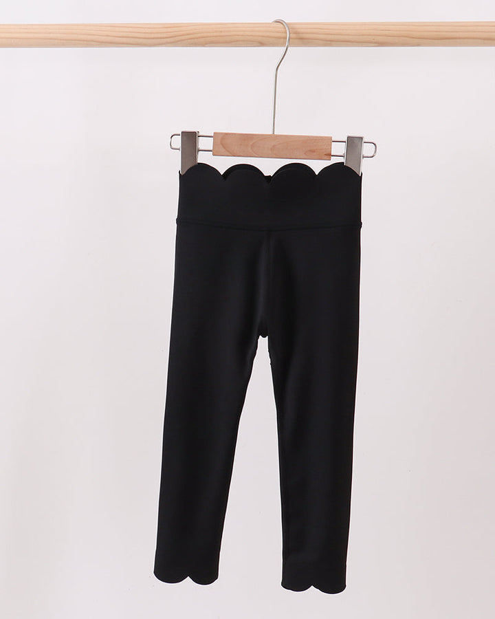 Black pants hanging on a wooden hanger against a white background
