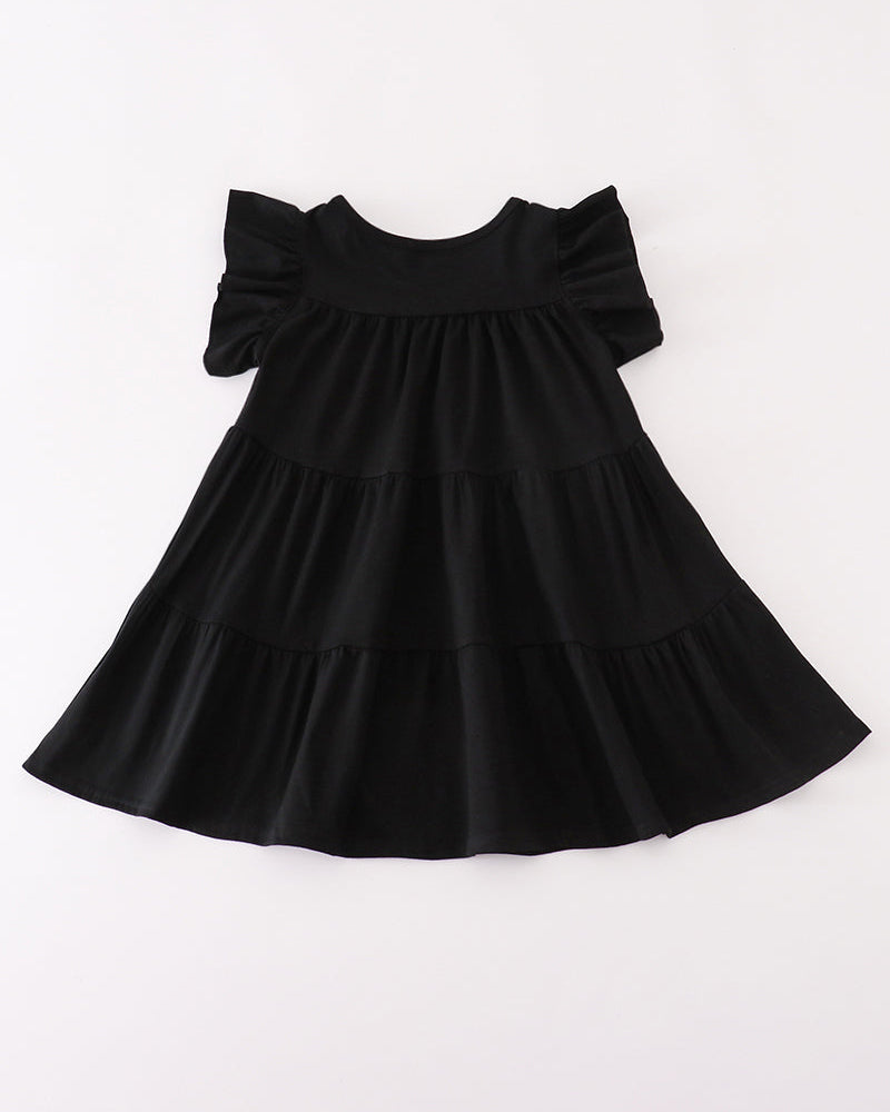 A black tiered baby dress with ruffled short sleeves, laid flat against a plain white background.