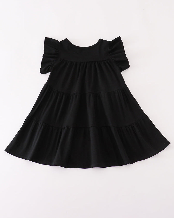 A black tiered baby dress with ruffled short sleeves, laid flat against a plain white background.