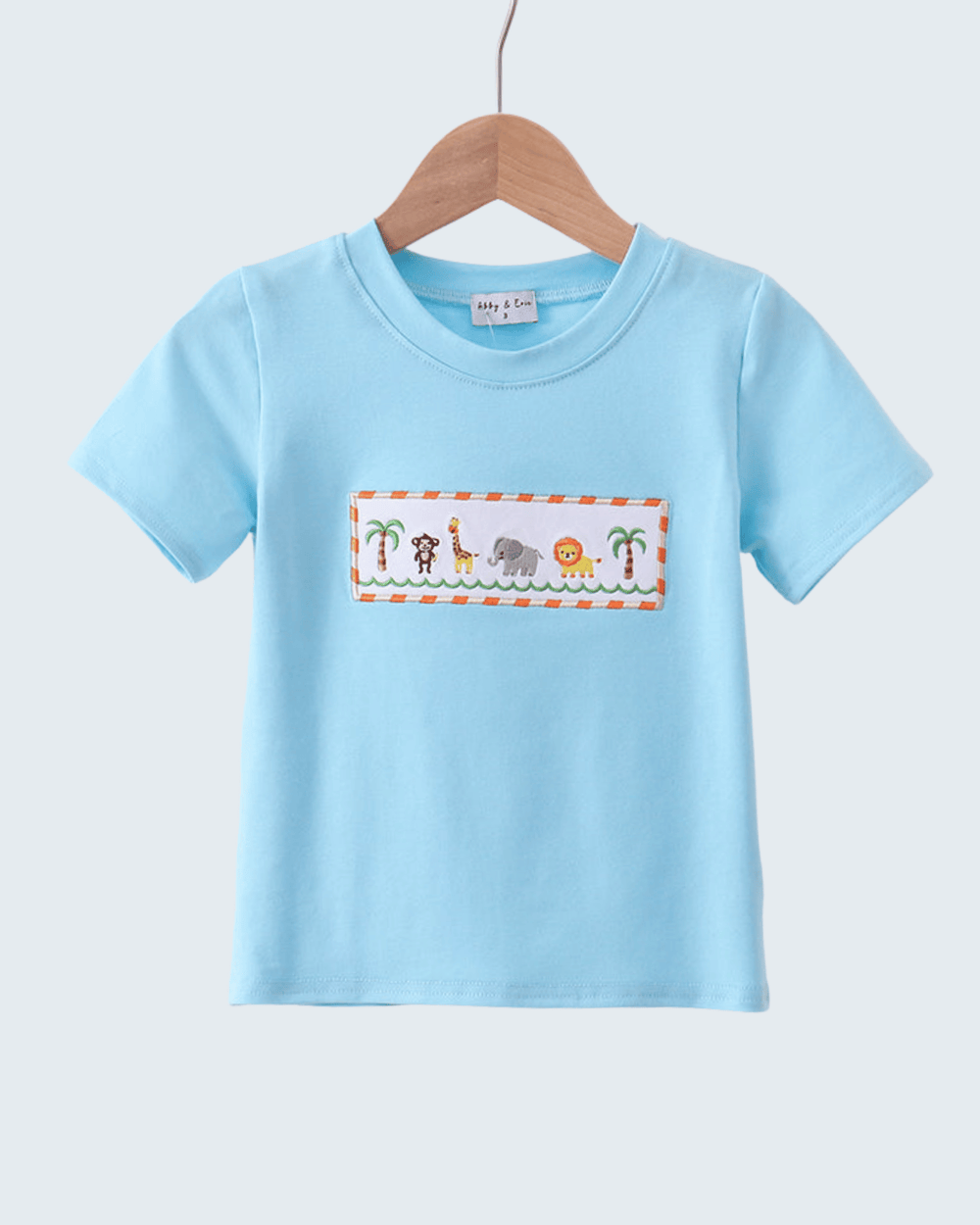 Light blue t-shirt with a colorful animal design on a hanger against a light gray background