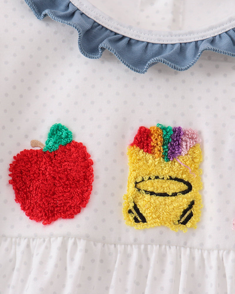 Girls white dotted dress bodice close-up with red, yellow, green, purple crayon appliques