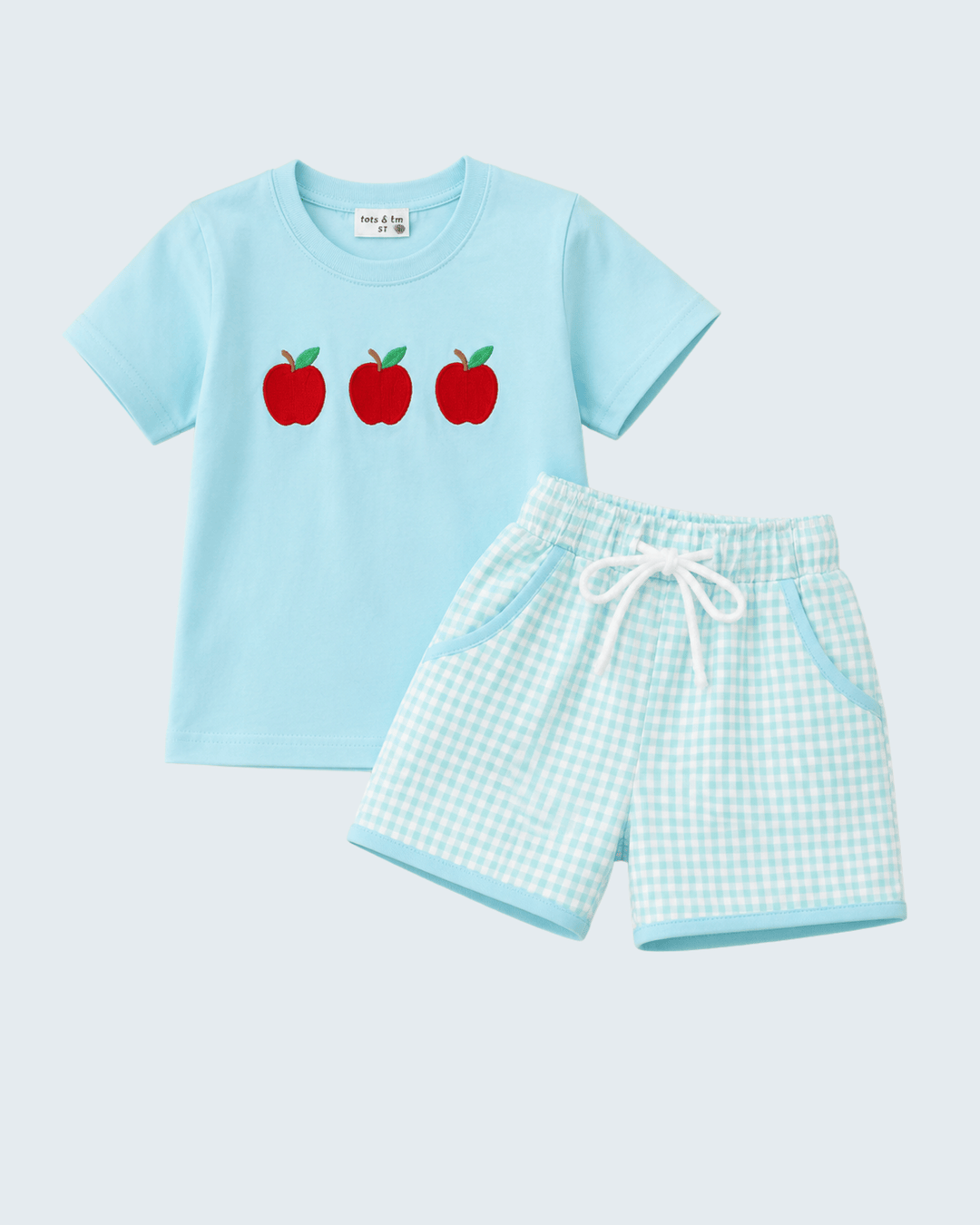 Light blue t-shirt with red apples and matching shorts on a light gray background