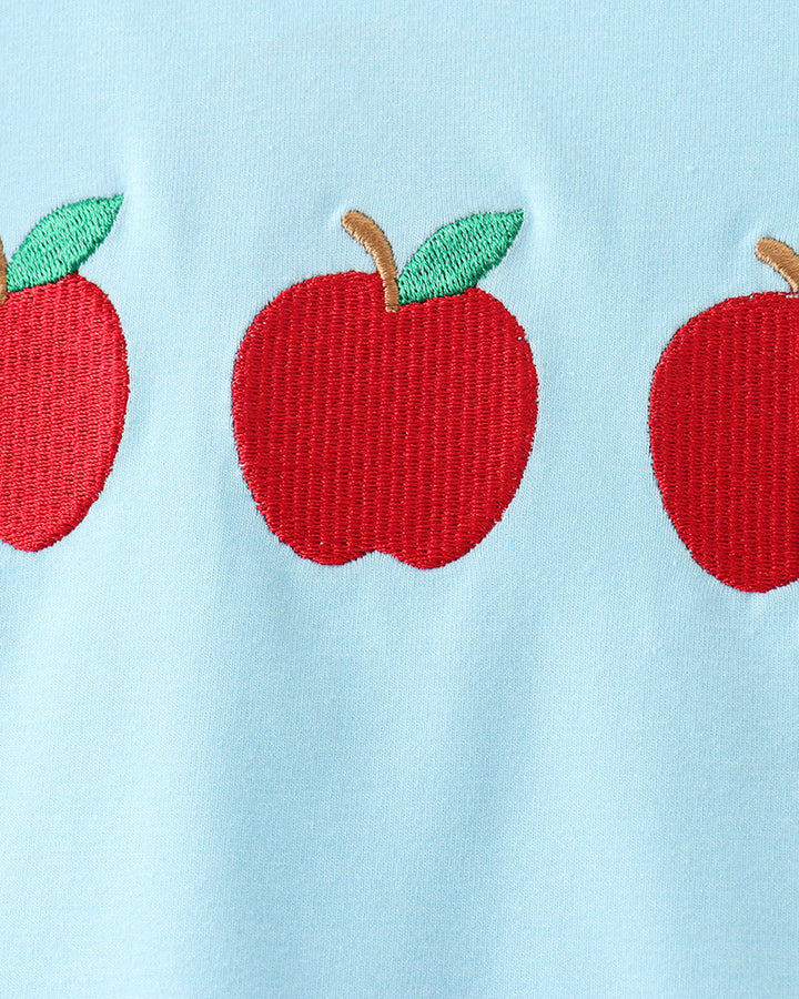 Light blue fabric with red apple appliqués and green leaves.