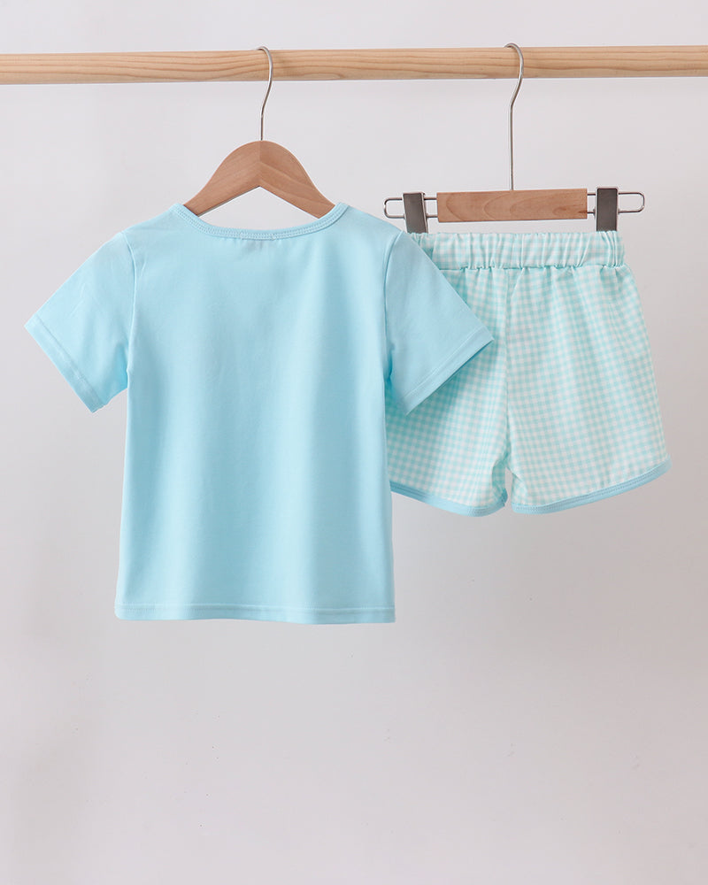 Light blue t-shirt and shorts set hanging on a wooden rack against a plain background