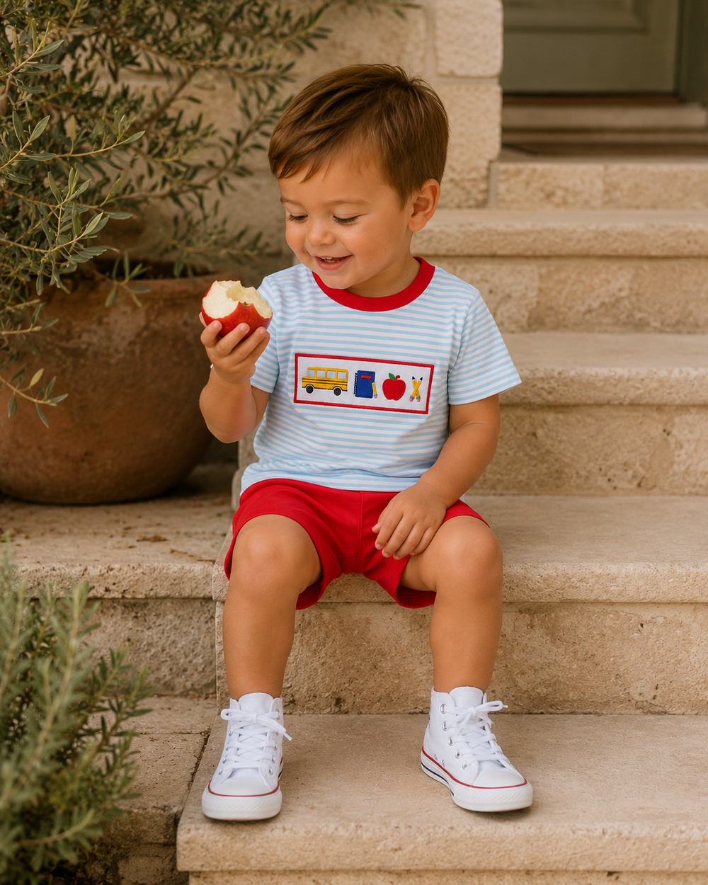 Children's light blue striped tee with red collar and red shorts worn with white sneakers.