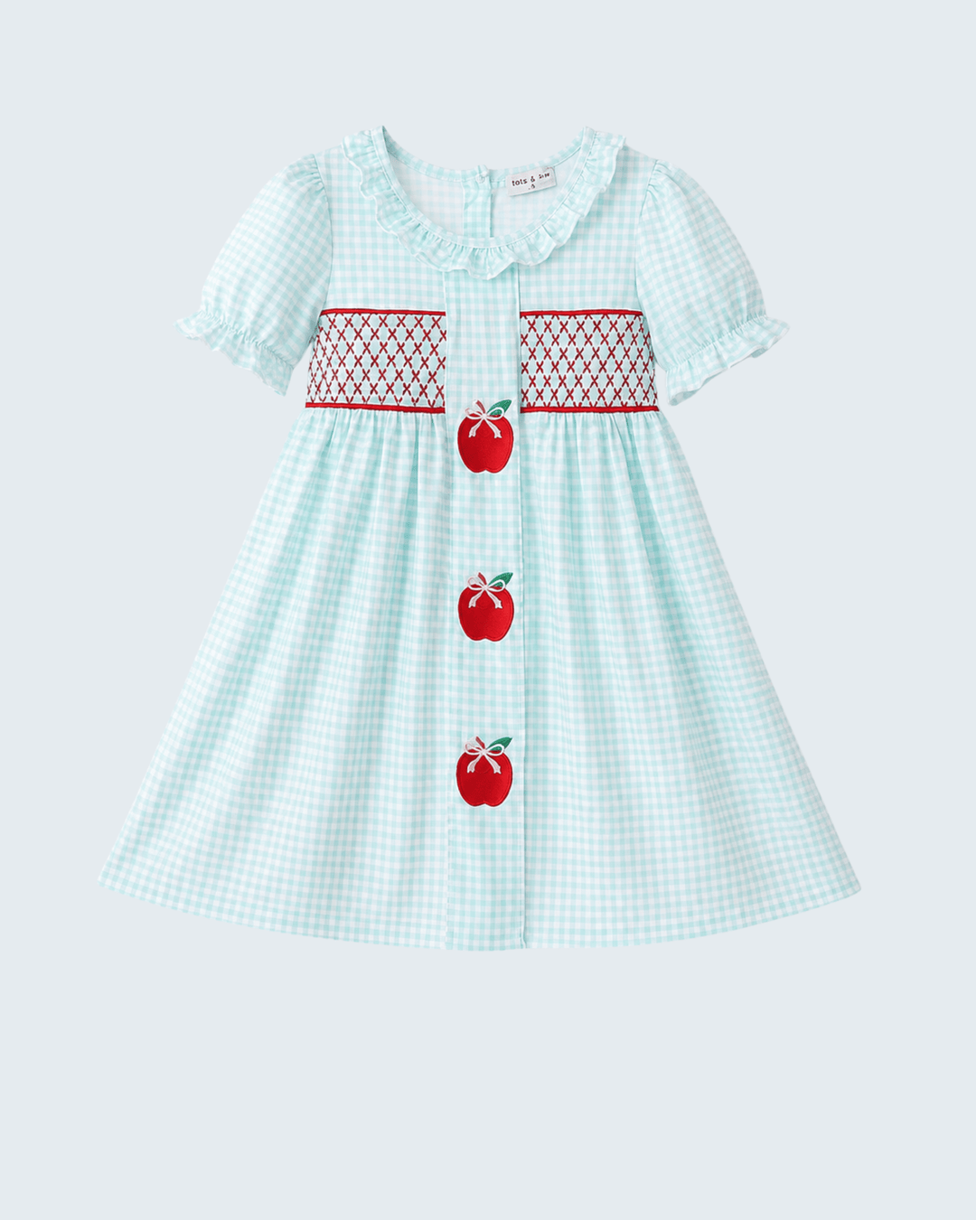 Children's dress with apple design on a light blue background