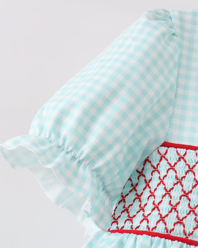 Close-up of a light blue checkered dress with red embroidery on a white background