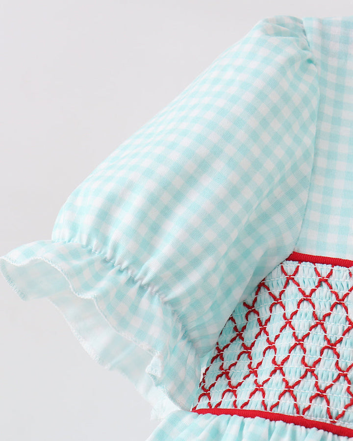 Close-up of a light blue checkered dress with red embroidery on a white background