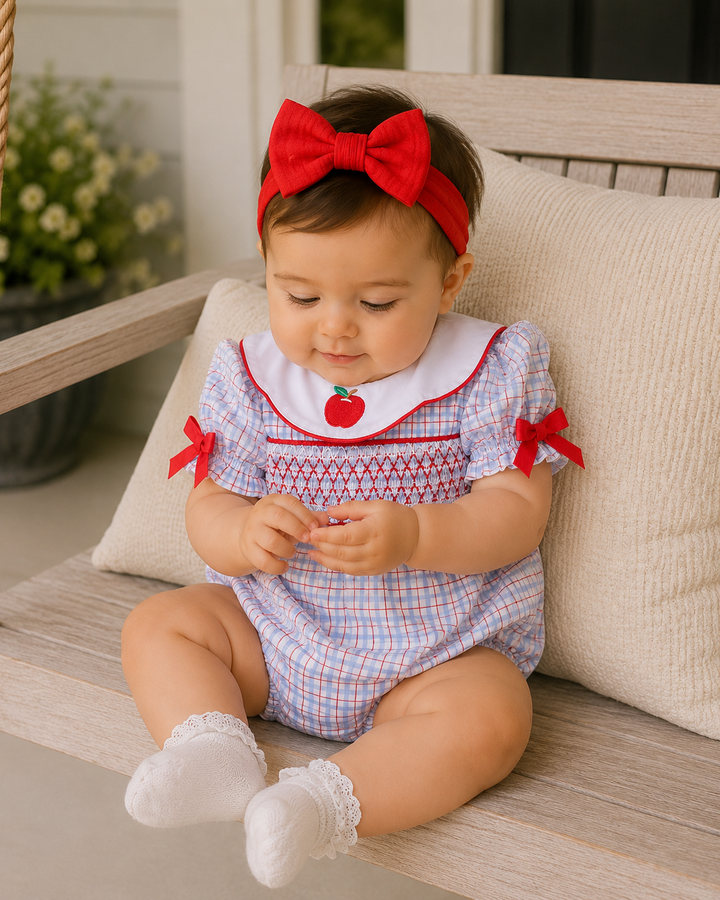 Baby girl is sitting on a porch swing playing with her hands