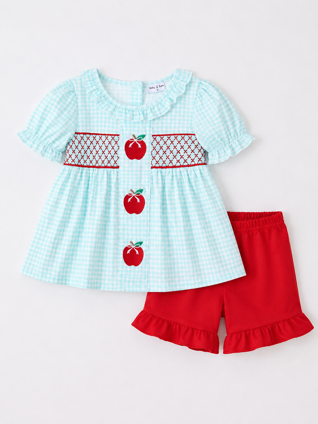 Children's outfit with a light blue checkered top and red shorts on a white background