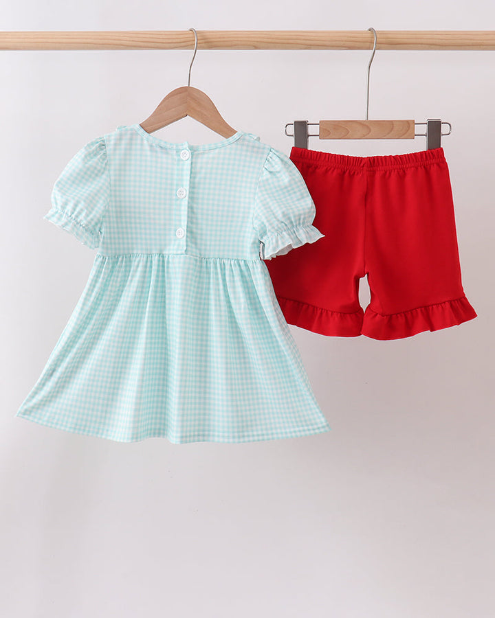Light blue checkered dress with ruffled sleeves and red shorts on hangers against a white background