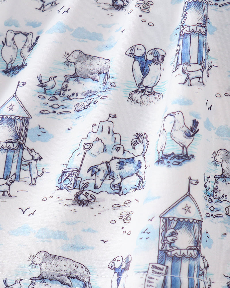 Fabric with a blue and white pattern of beach-themed illustrations including penguins, seals, and beach huts.