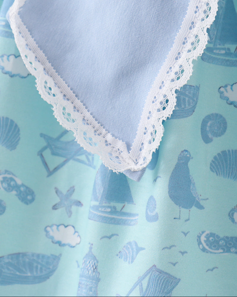 Light blue dress with white lace trim on a blue fabric background with nautical patterns.